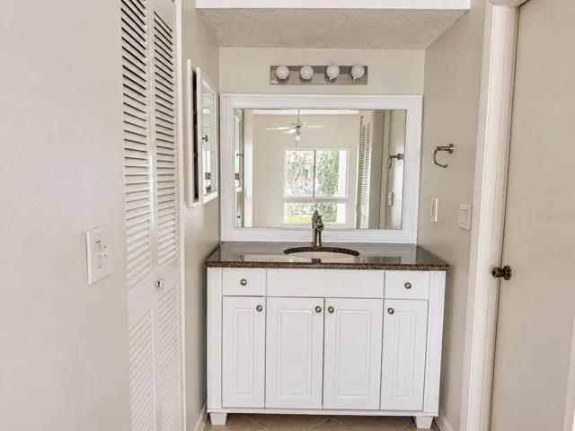 Updated primary vanity area; walk-in closet at left.  Shower and toilet area at right.