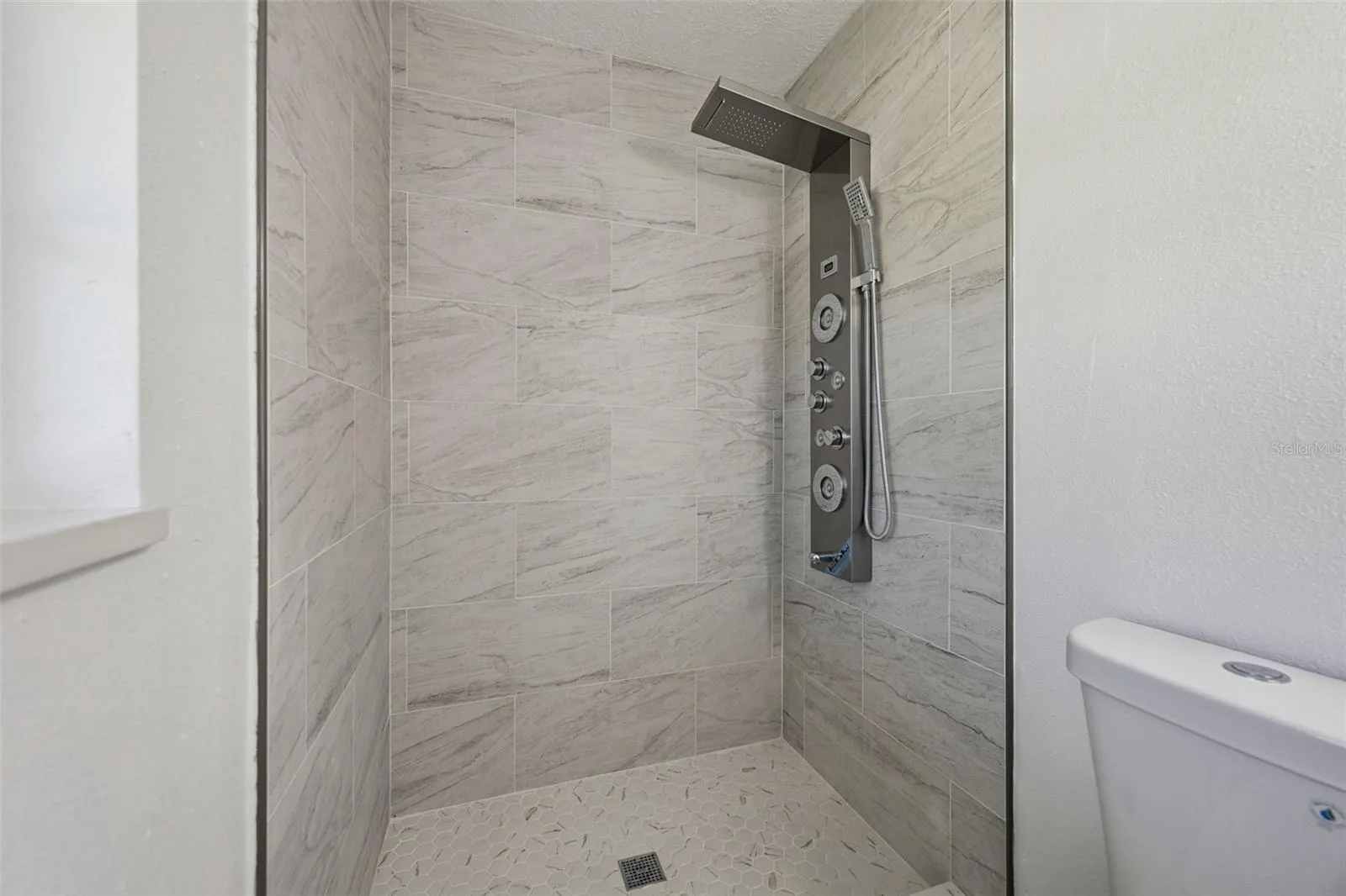 Walk-In Tile Shower: Custom step-in shower with marble-style tile surround, mosaic floor tile, and multi-function shower panel.
