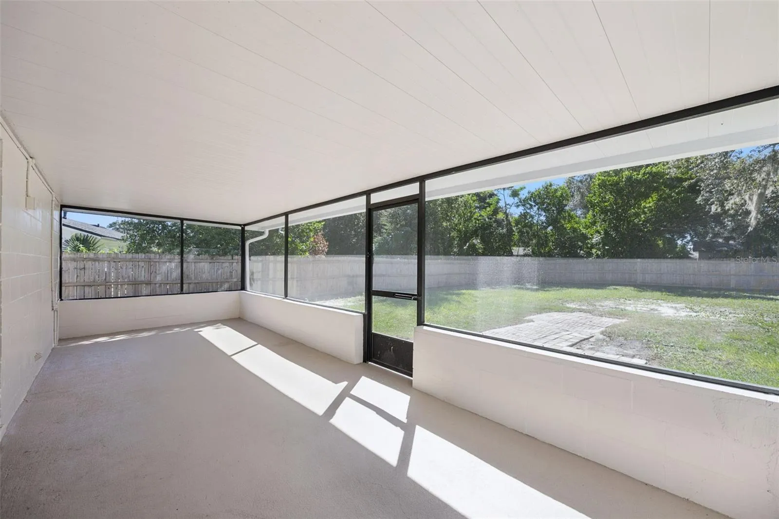 Screened Porch View: Interior view of the screened porch looking out to the expansive fully fenced backyard with screen door lawn access.