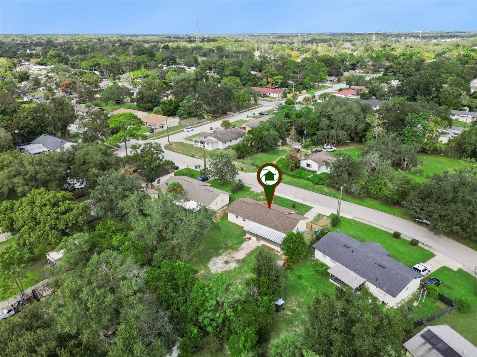 Aerial Neighborhood View: Elevated drone perspective highlighting the property with a location pin set against the surrounding tree-lined community.