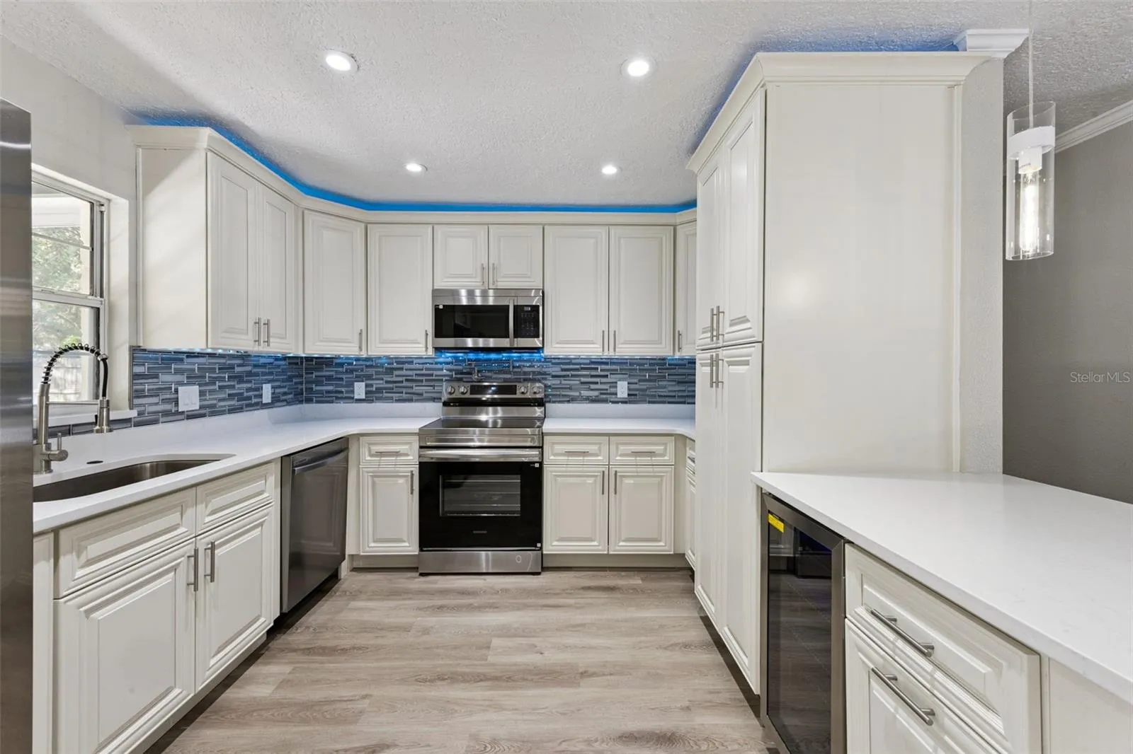 Kitchen Prep &amp; Cooking Zone: Functional kitchen layout with quartz countertops, decorative tile backsplash, electric range, and integrated under-counter wine fridge.