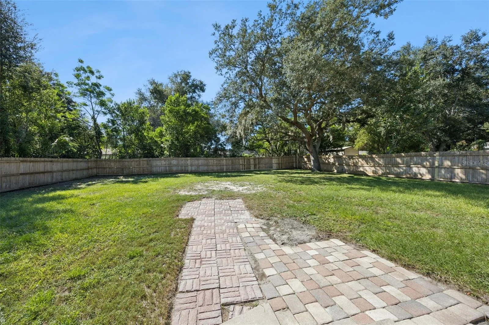 Paver Patio &amp; Yard View: Close-up of the brick paver pathway leading out into the spacious, private backyard.