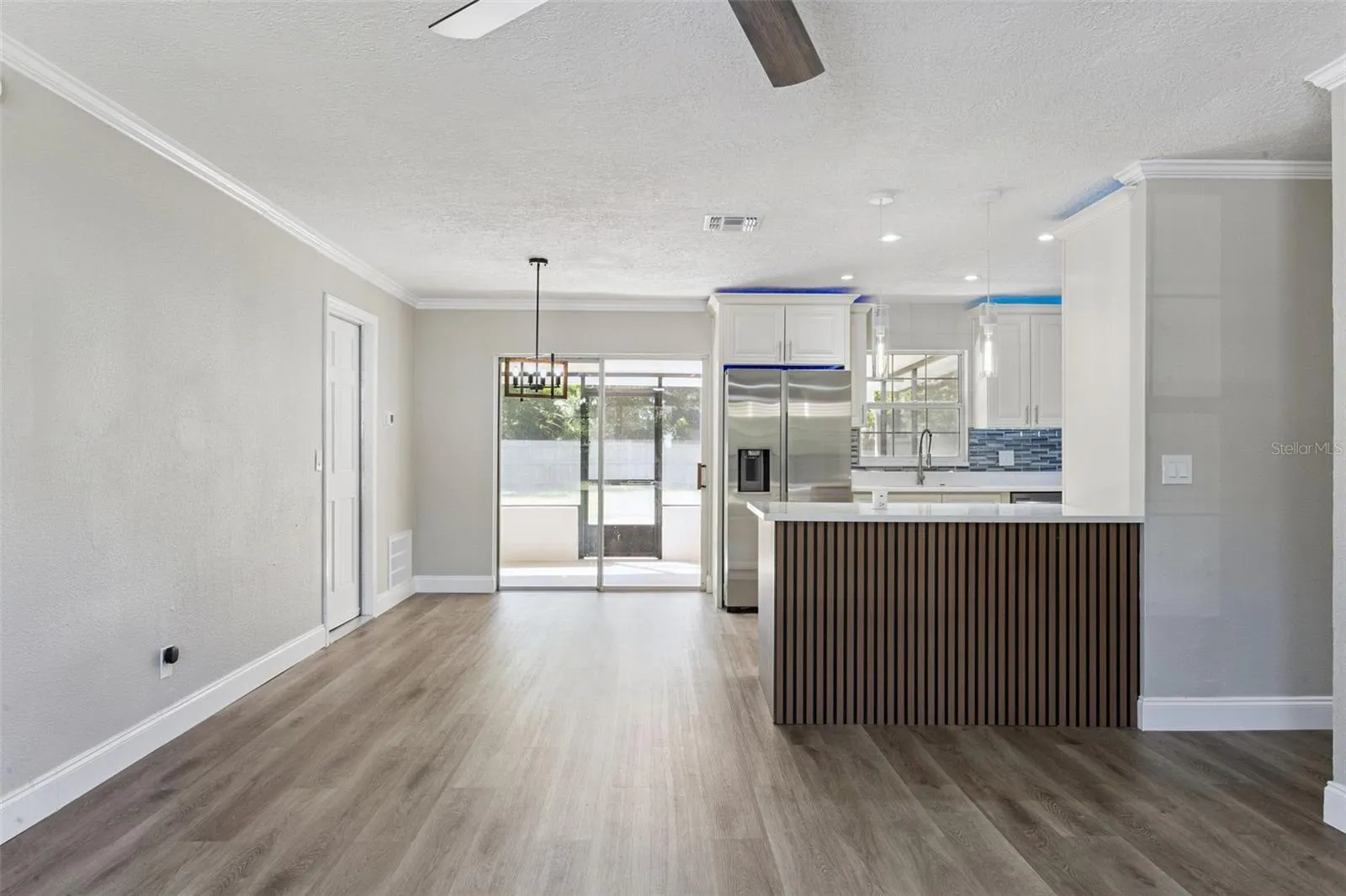 Dining &amp; Kitchen Transition: Seamless transition between dining and kitchen spaces with pendant lighting, sliding patio doors, and slatted island accents.