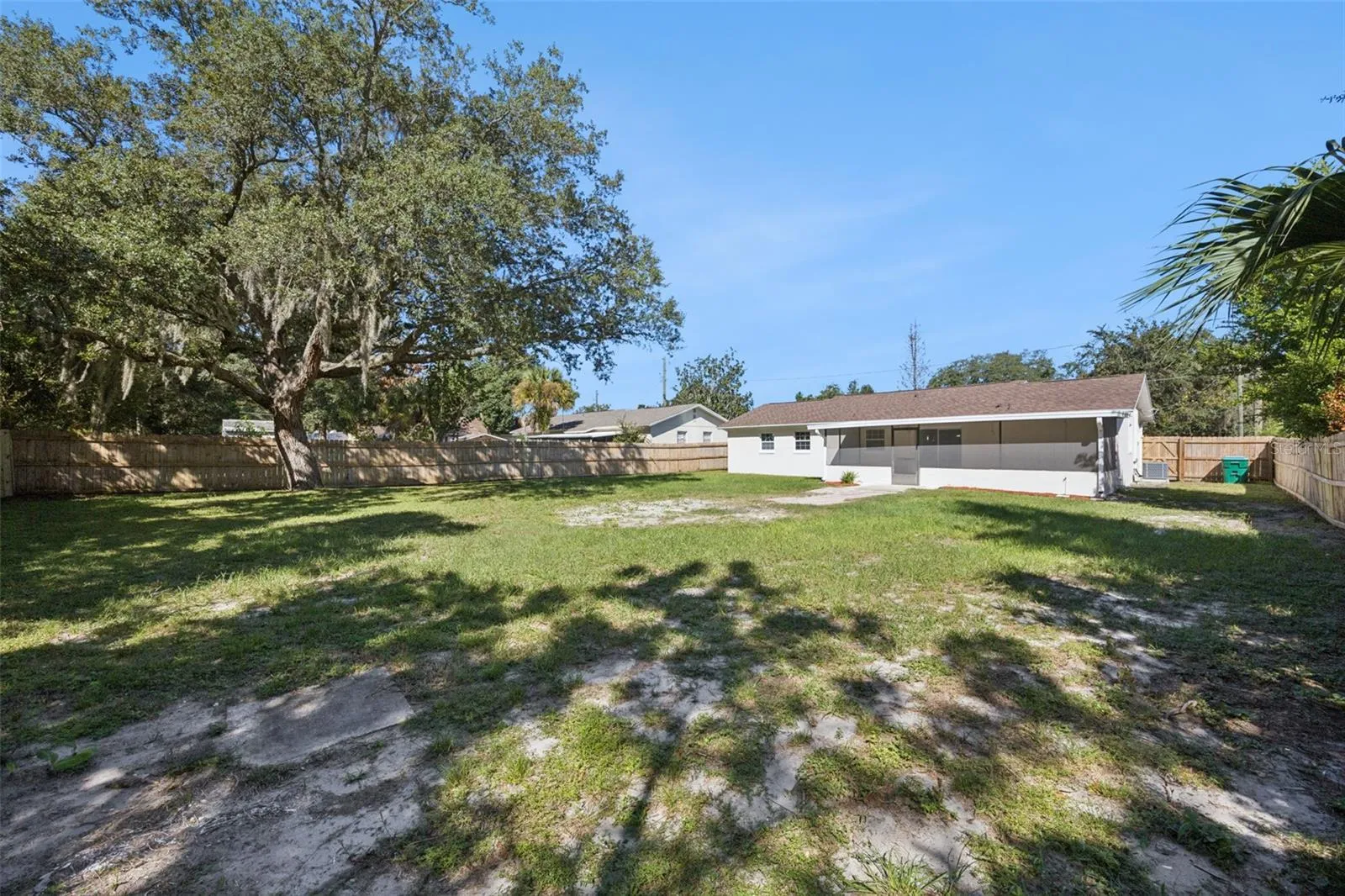 Yard Angle &amp; Oak Canopy: Wide view of the fully fenced rear yard highlighting lush green grass and a magnificent shade oak.