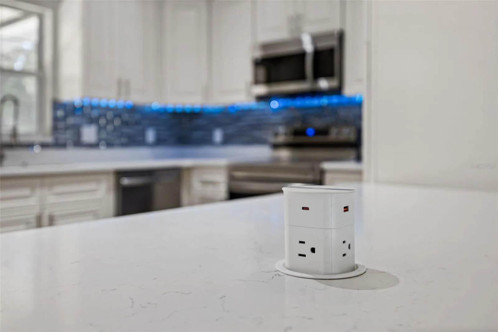 Pop-Up Countertop Outlet: Modern kitchen feature highlighting a pop-up island power hub with standard outlets and USB charging ports.