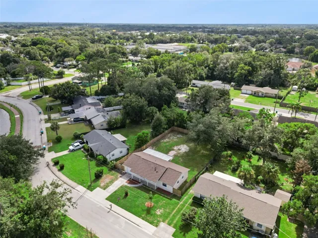 Aerial Neighborhood Overview: Elevated aerial shot highlighting the home's location within the surrounding tree-lined neighborhood.