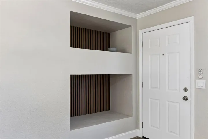 Foyer Architectural Niches: Entryway detail featuring dual built-in recessed display niches with decorative slatted wood backdrops.