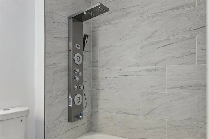 Luxury Shower Panel Detail: Close-up of the stainless steel shower panel featuring a rainfall showerhead, handheld sprayer, and massage body jets