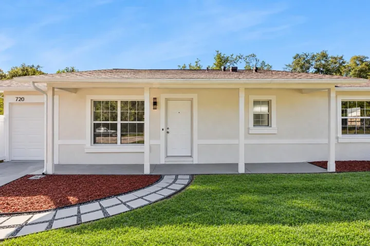 Covered Front Entry &amp; Walkway: Welcoming covered entryway featuring a custom paver walkway, fresh mulch landscaping beds, and a clean white front door