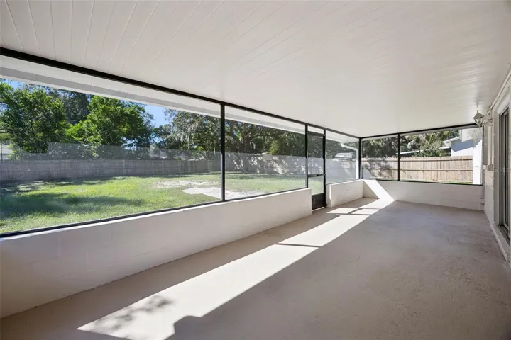 Expansive Lanai Interior: Broad view across the covered screened porch, providing a protected outdoor retreat overlooking the rear grounds