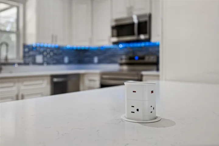 Pop-Up Countertop Outlet: Modern kitchen feature highlighting a pop-up island power hub with standard outlets and USB charging ports.