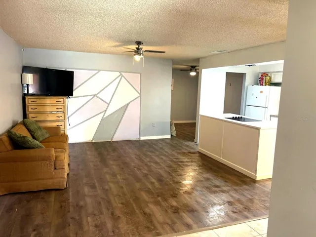 Spacious living room with ceiling fan and wood-look floors