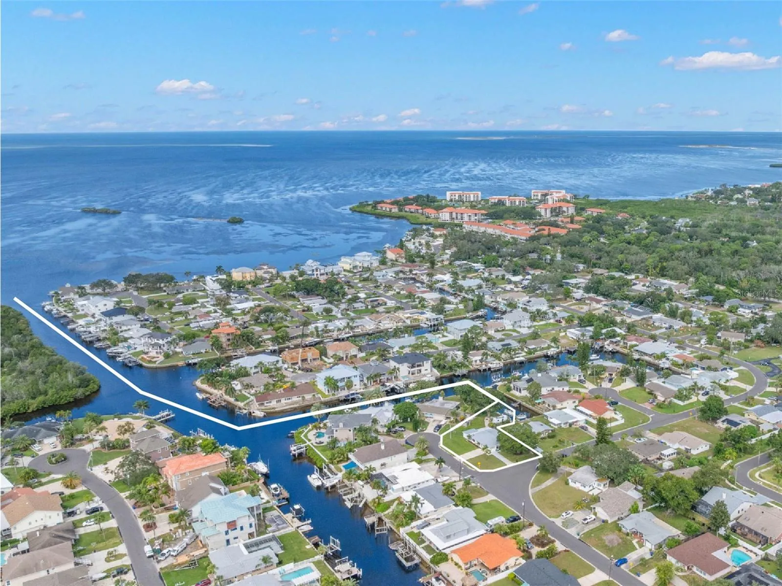 A sweeping aerial view puts the waterfront setting in perspective, showing Baywood Village’s canal system winding toward the open Gulf of Mexico — a standout location for boaters who want direct saltwater access close to home.