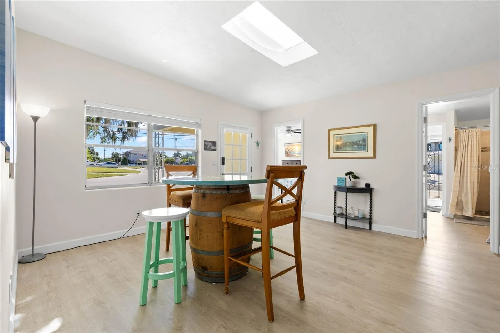 The bright dining area features 2025 luxury vinyl plank flooring, a skylight overhead, broad front windows, and plenty of room for everyday meals or entertaining.