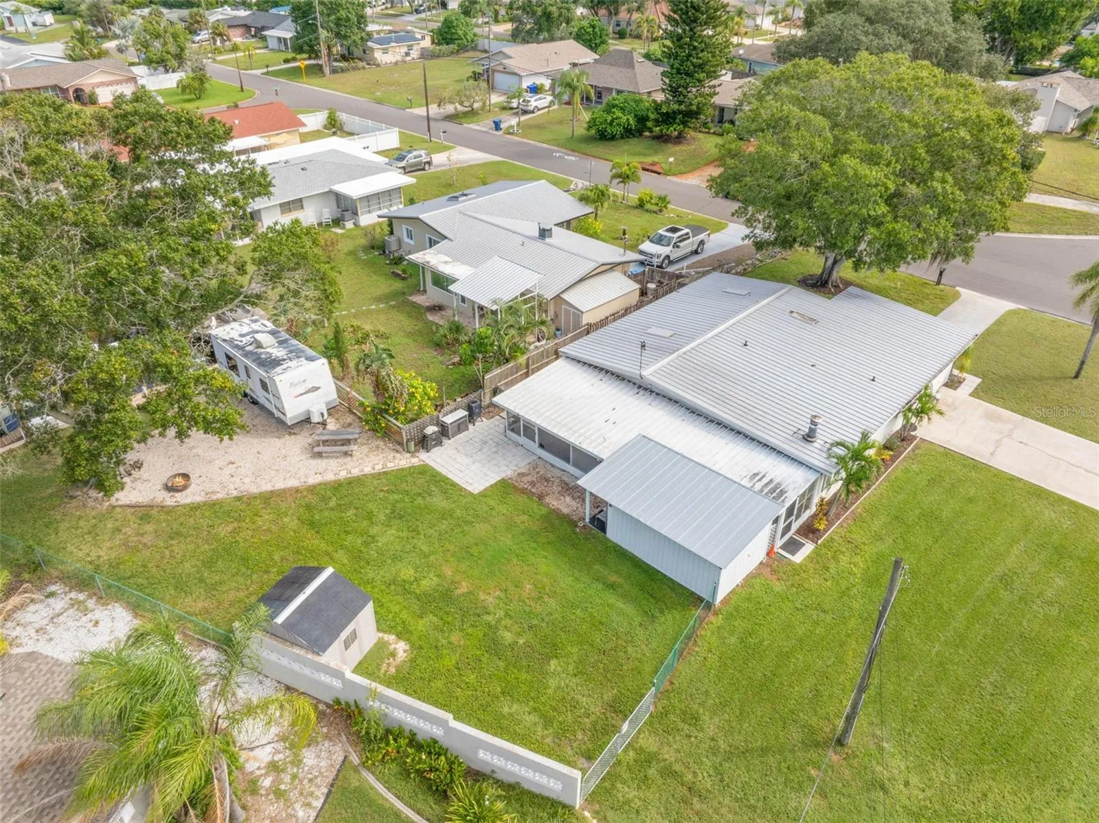 An aerial view shows just how much this property offers, with a broad backyard, RV parking area, screened lanai, workshop/storage space, and plenty of room to spread out.