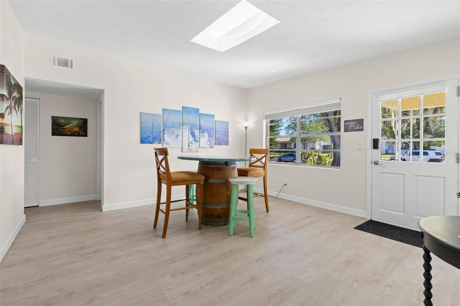Step inside to a bright, open dining area with 2025 luxury vinyl plank flooring, a skylight overhead, and broad front windows that fill the space with natural light.