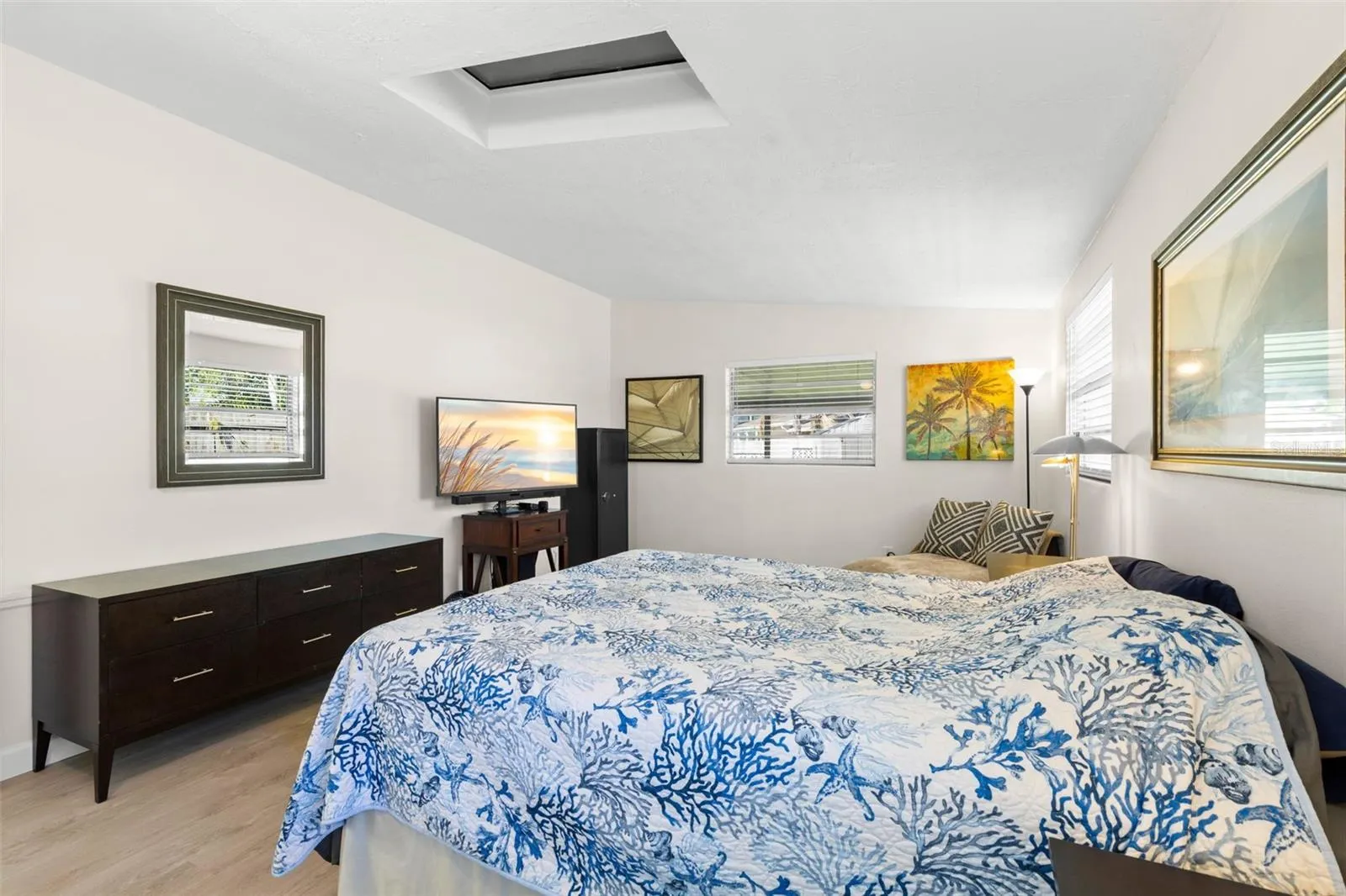 The primary bedroom offers exceptional space for both sleeping and lounging, with multiple windows, a skylight, neutral tones, and luxury vinyl plank flooring (2025) keeping the room bright and cohesive.