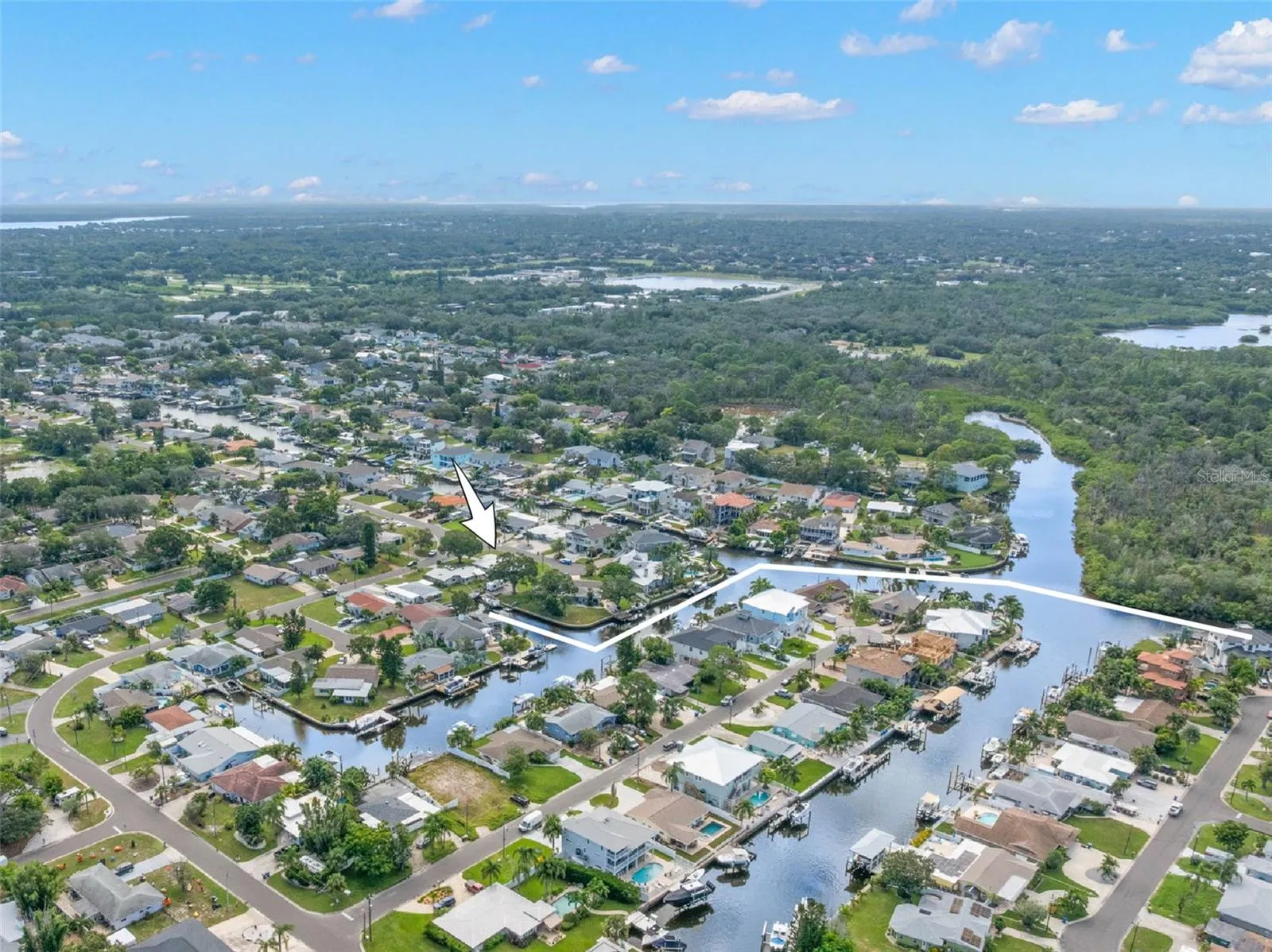 An aerial view showcases Baywood Village’s network of saltwater canals and the home’s close-to-the-water setting, with direct Gulf access from the neighborhood and easy reach of Tarpon Springs, Fred Howard Park, Sunset Beach, and Wall Springs Park.