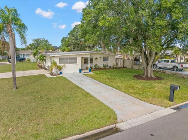 An elevated view highlights the home’s generous 11,800-square-foot corner setting, with a broad lawn, long driveway, mature shade trees, and the extra breathing room created by the one-and-a-half-lot property.