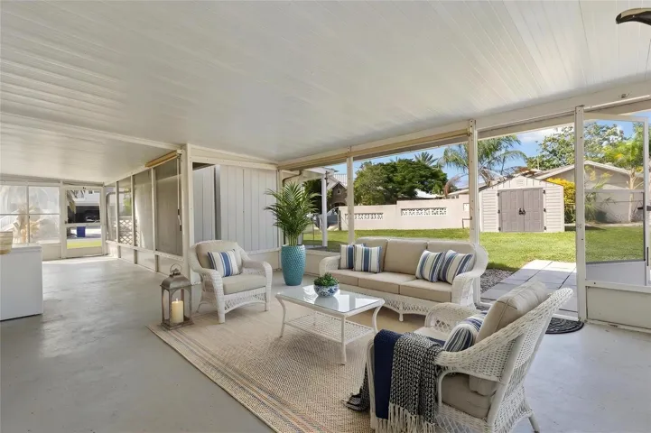 The screened lanai opens directly to the backyard, creating a generous covered space for dining, lounging, or entertaining, with easy access to the lawn and outdoor storage shed.