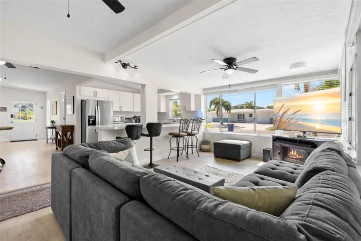 Expansive windows flood the living room with natural light, while the open connection to the updated kitchen, breakfast bar, ceiling fan, and fireplace creates a bright, comfortable gathering space.