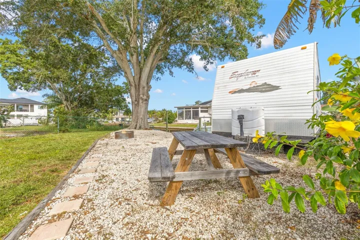 The oversized side yard offers dedicated space for RV, boat, or trailer parking, along with a gravel picnic area beneath a mature shade tree—another benefit of this generous 11,800-square-foot property.