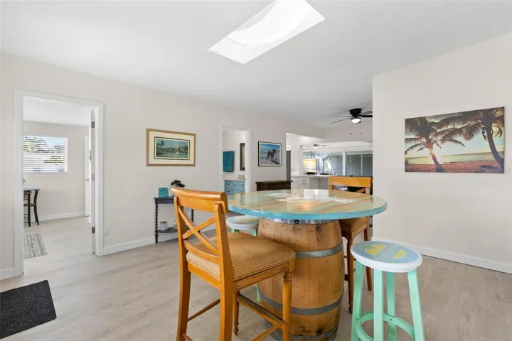 The spacious dining area is filled with natural light from the skylight and flows easily into the adjoining kitchen and living spaces, with 2025 luxury vinyl plank flooring creating a clean, cohesive look.