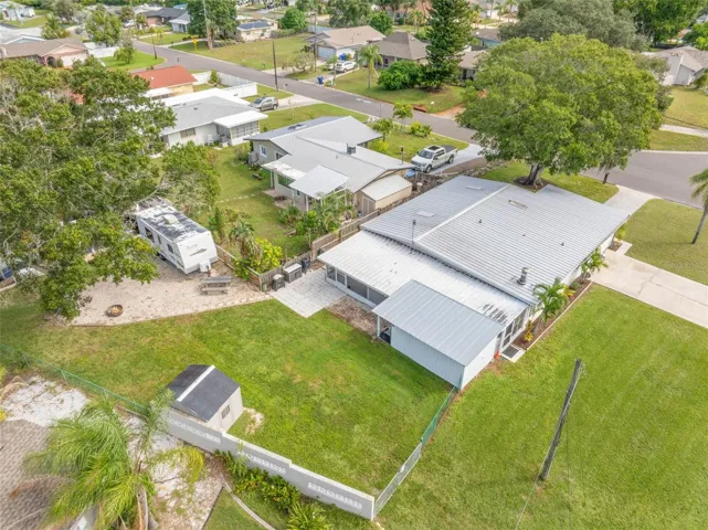 An aerial view shows just how much this property offers, with a broad backyard, RV parking area, screened lanai, workshop/storage space, and plenty of room to spread out.