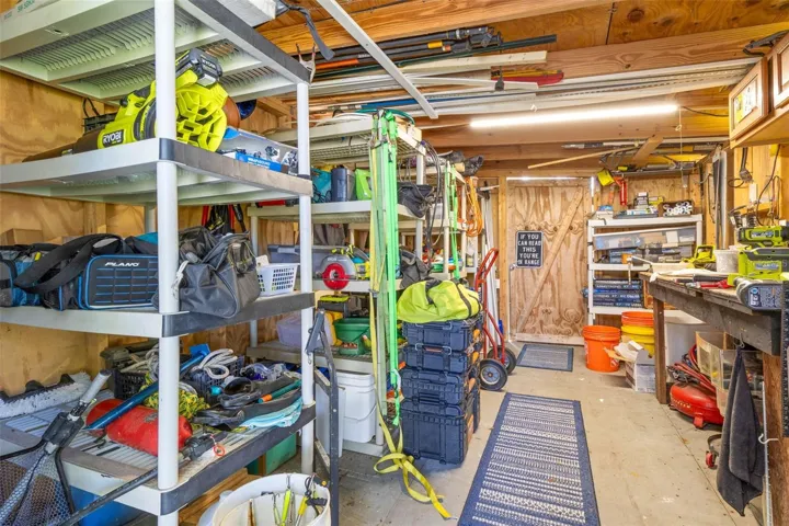 A dedicated workshop offers serious utility with abundant shelving, a long workbench, overhead storage, lighting, and plenty of room for tools, fishing gear, projects, and everyday equipment.