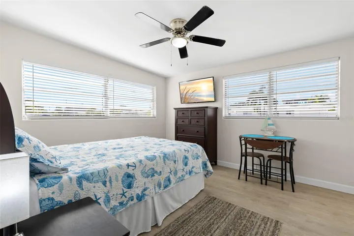 The third bedroom features two walls of windows, a ceiling fan, neutral tones, and luxury vinyl plank flooring (2025), with enough space for both sleeping and a small sitting or study area.