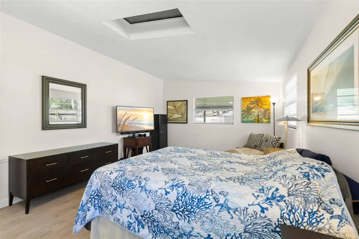 The primary bedroom offers exceptional space for both sleeping and lounging, with multiple windows, a skylight, neutral tones, and luxury vinyl plank flooring (2025) keeping the room bright and cohesive.