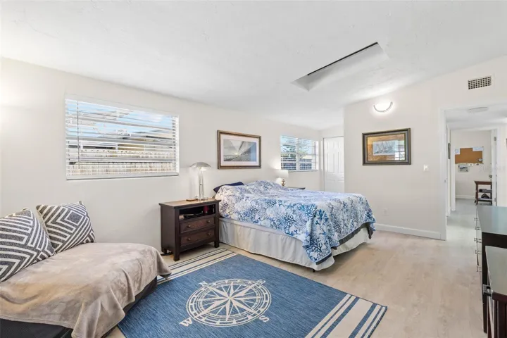 The spacious primary bedroom easily accommodates a king-size bed and a dedicated sitting area, with multiple windows, a skylight, neutral tones, and luxury vinyl plank flooring (2025) adding to the bright, open feel.