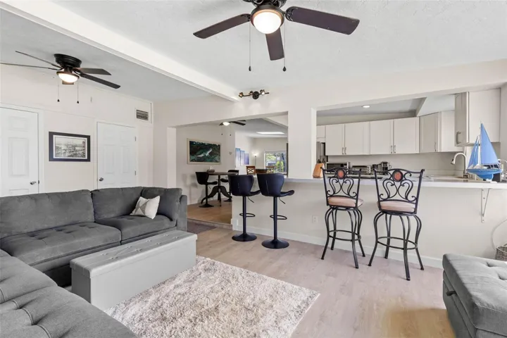 The spacious living area features dual ceiling fans, a soft neutral color palette, and 2025 luxury vinyl plank flooring, with an open connection to the kitchen and breakfast bar that keeps the space feeling relaxed, connected, and easy to use.