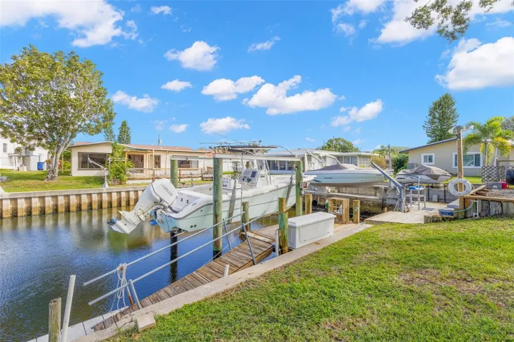 The canal frontage is equipped for easy days on the water, with a 10,000-pound boat lift, wooden dock, railed access walkway, waterside storage, and approximately 60 feet of seawall, all just steps from the backyard.