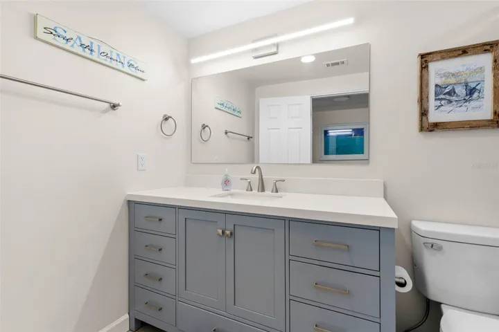 The remodeled primary bath (2025) features a wide gray vanity with abundant drawer storage, a sleek white countertop, oversized mirror, and contemporary linear lighting.