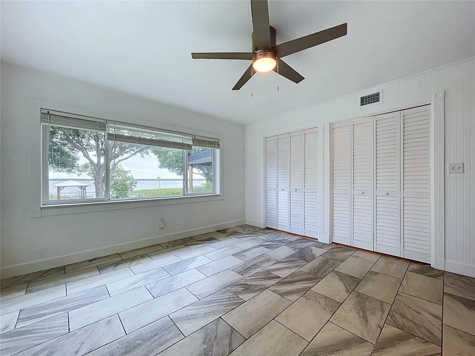 Bedroom 1 with ceiling fan and tile-pattern flooring