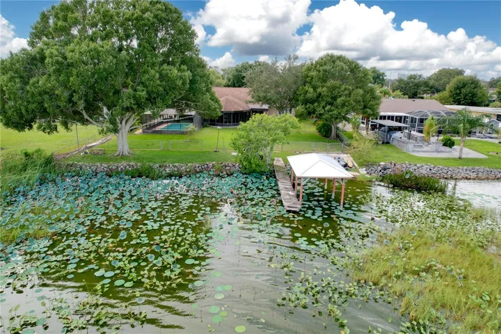 Aerial view from water of backyard, dock, and ramp