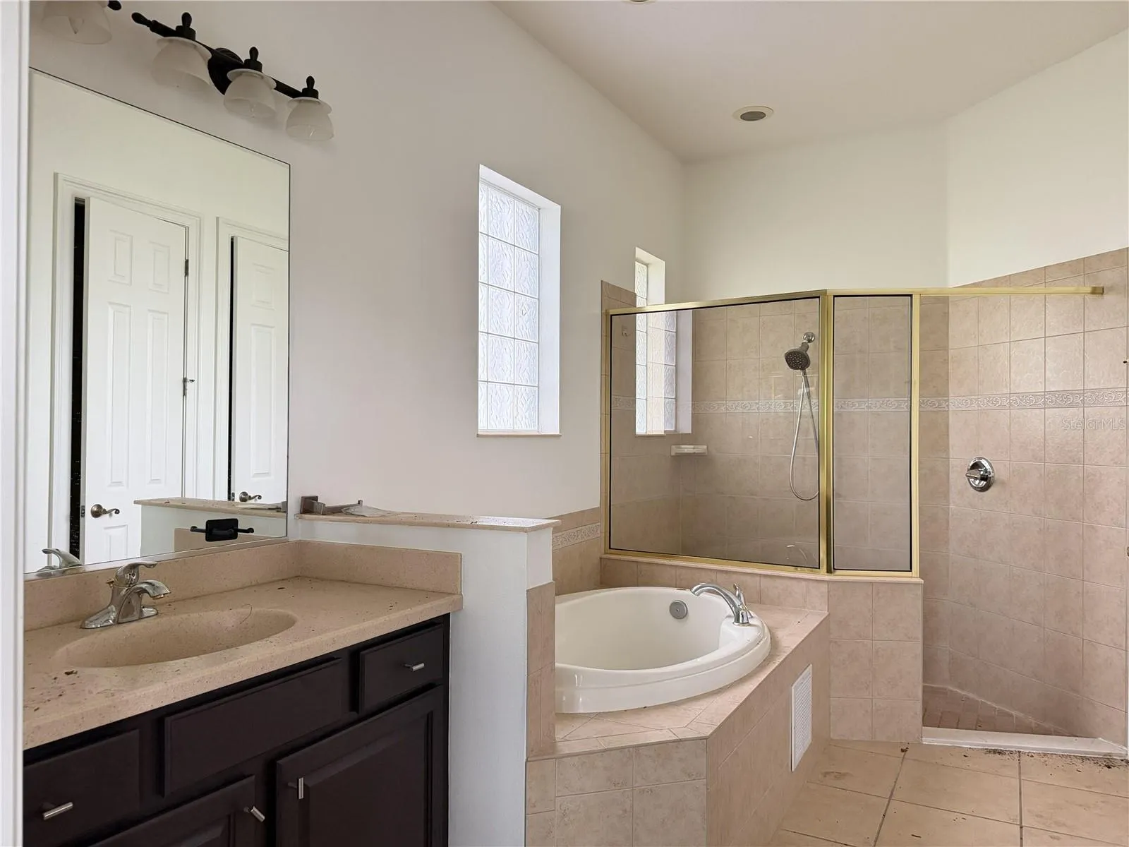 Primary bath with soaking tub, tiled shower, and separate sink vanities.