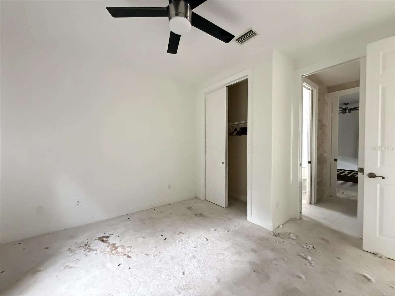 Additional view of stained carpeting and debris in Bedroom 2.