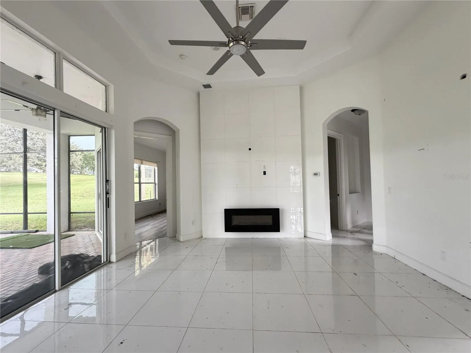 Great room with high ceiling, ceiling fan, and electric fireplace.