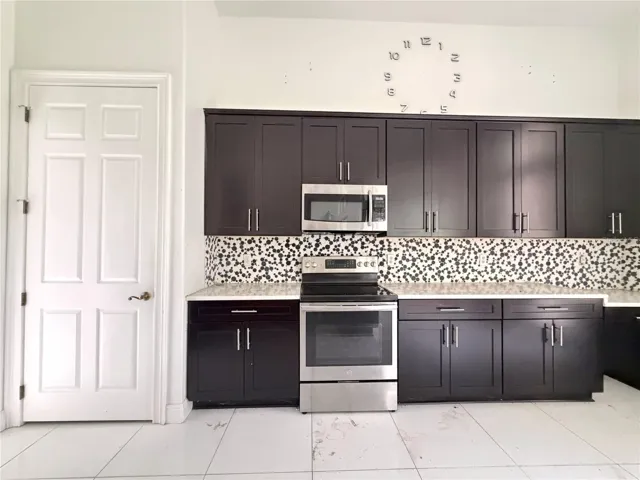 Electric range, microwave, patterned backsplash, and cabinet storage.