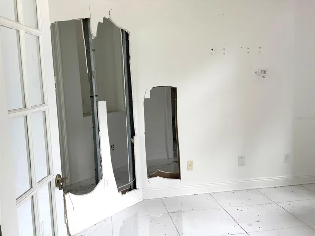 Study/den with missing drywall and exposed wall framing requiring restoration.