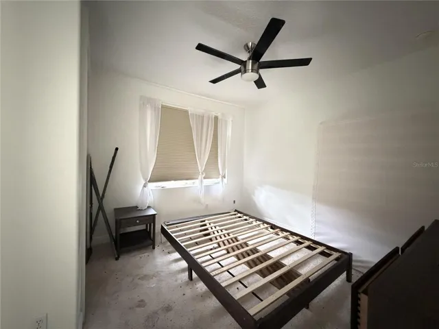 Third bedroom with ceiling fan and exterior window; carpet shows soiling.