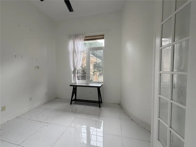Separate study/den with ceiling fan, window, and glass-paneled door.