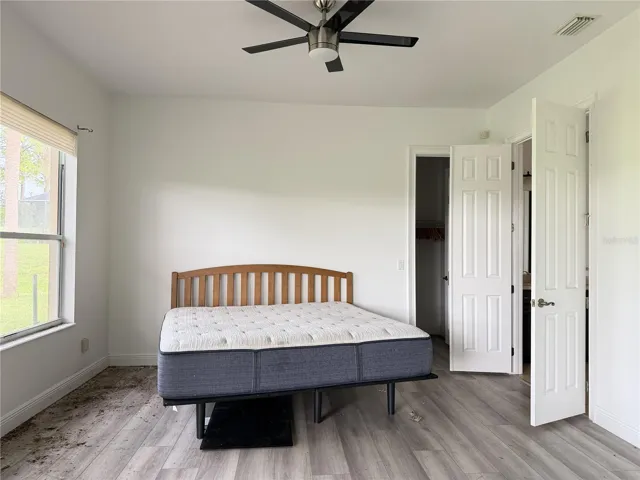 Main-floor primary bedroom with luxury vinyl flooring and ceiling fan.