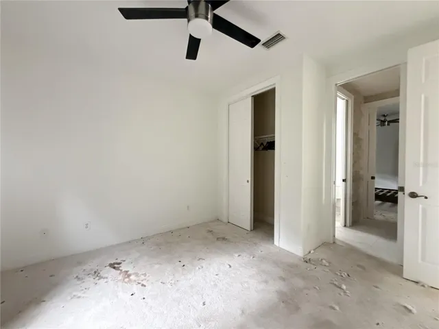 Additional view of stained carpeting and debris in Bedroom 2.
