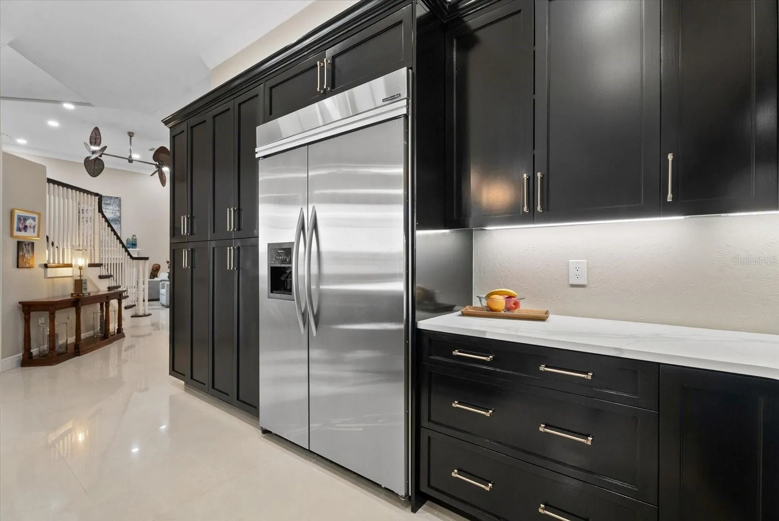 High end stainless steel appliances and a bank of custom cabinets are shown.  There is also a walk-in pantry and two other closets accessible to the kitchen and dining room