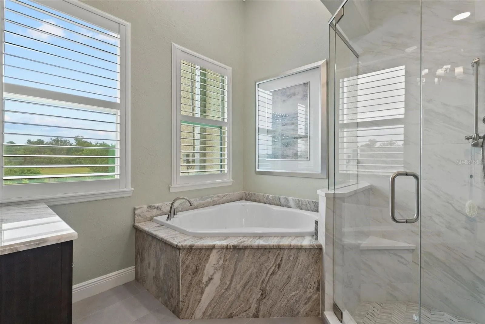 A step in shower and deep garden tub are tucked into the corner of the ensuite bath of the primary suite