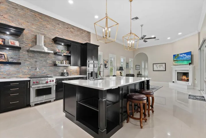 The chefs kitchen features new cabinets, a stone backsplash, pot filler over the gas stove, a large island, and a view into the family room