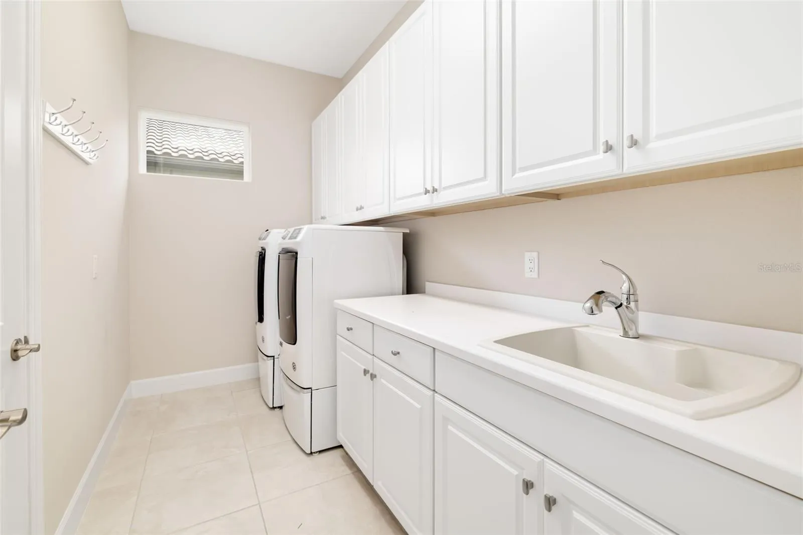 Spacious laundry room boasts an abundance of cabinetry and  counter space with sink and includes the  washer and dryer